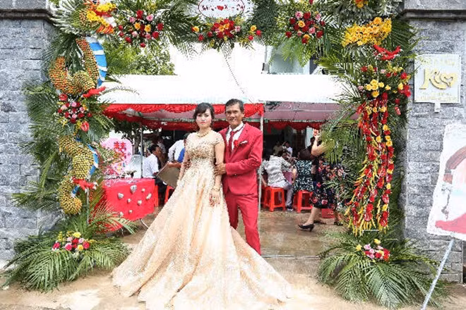 Cô dâu chú rể trước cổng chào được thiết kế tỉ mỉ, công phu từ hàng nghìn trái cau non và ớt. Đây là công trình do chính chú rể làm mất hai ngày trời.