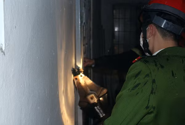 Lực lượng chức năng phá cửa căn hộ. Ảnh: Hoàng Anh.