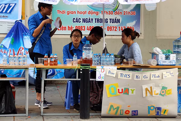 Bảng thông báo giữ xe và quầy nước miễn phí đầy màu sắc của Đoàn thanh niên phường Mai Dịch tại điểm thi THCS Nghĩa Tân.