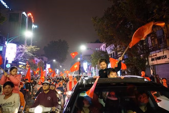 Đường phố rực rỡ màu cờ trong đêm chiến thắng của U23 Việt Nam. Dù nhiệt độ ngoài trời khá lạnh khoảng hơn 17 độ C nhưng nhiều gia đình vẫn cho con nhỏ theo mình xuống phố ăn mừng.