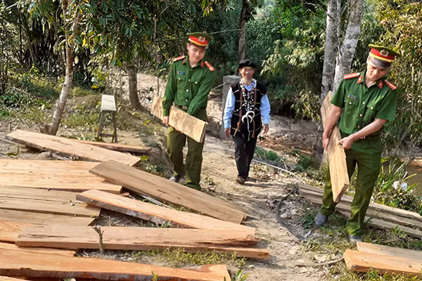 Cán bộ Công an xã A Nông vận chuyển vật liệu giúp người dân bắc cầu qua suối.