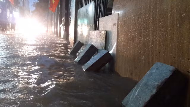 Khu vực ngõ 99 Định Công, nước dâng cao khiến người dân phải che chắn tránh nước vào nhà. Ảnh: V.nhi
