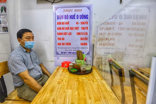Khách hàng ngồi ăn trong quán đảm bảo giãn cách và tấm chắn tại chỗ ngồi theo quy định phòng dịch.