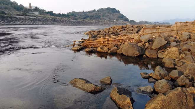 Lòng hồ thủy điện cạn trơ đáy, lộ ra hàng loạt khối đá tảng và bê tông.