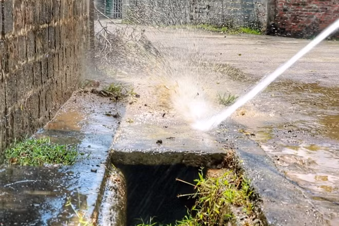 Bùn đất sau ngập dài ngày được xịt rửa sạch khỏi mặt đường.