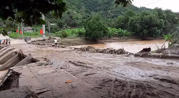 Hàng trăm mét khối bùn đất để lại sau khi lũ tràn qua đường.