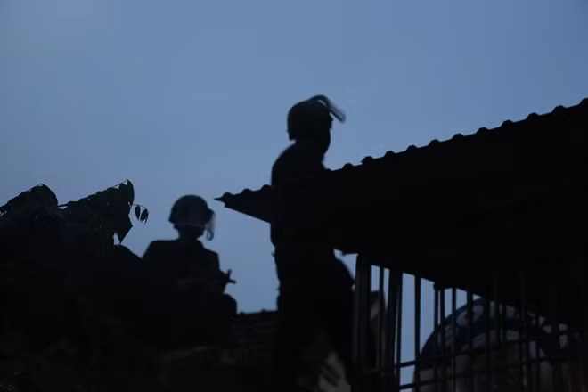 Cảnh sát cơ động áp sát phía sau ngôi nhà, sẵn sàng tấn công khi có lệnh