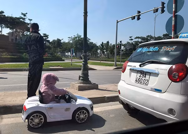 Hình ảnh người bố cho con chơi trên đường giao thông. Ảnh: Hồ Hà.