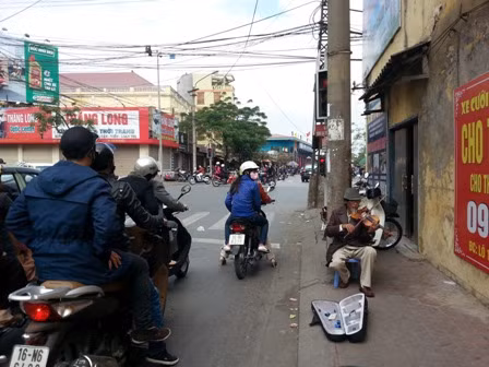 Hình ảnh người nghệ sĩ già chơi đàn nơi ngã tư