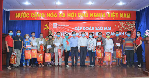 Ông Lê Xuân Quế - Phó Tổng Giám đốc Tập đoàn Sao Mai (thứ 7 phải qua) phát quà tại phường Đông Xuyên, Tp. Long Xuyên.