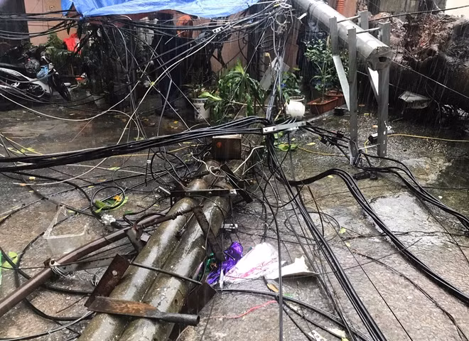 Tại phố Lý Nam Đế, một cây sấu to bị đổ trong mưa kéo theo cột điện đè vào nhà dân. Rất may không thương vong về người.