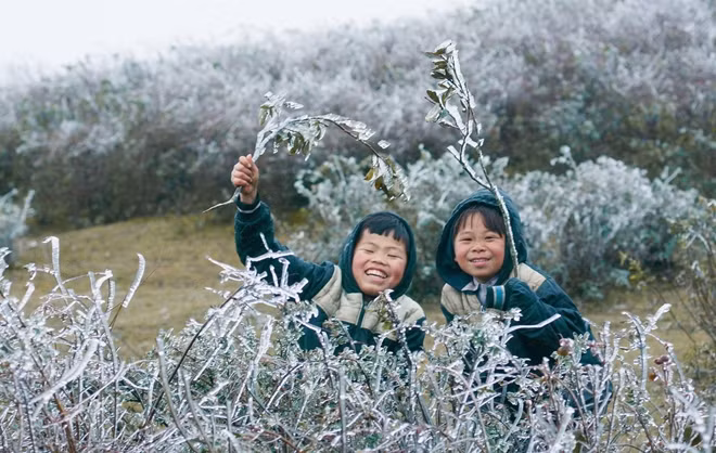 Hai em nhỏ vùng cao rạng rỡ vui đùa trong băng tuyết lạnh giá.