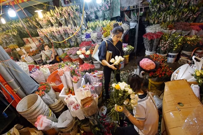 Cảnh mua bán tấp nập diễn ra từ sáng sớm bên trong chợ hoa Quảng Bá. Một cô gái đang chọn cho mình những bông hồng trắng tinh khôi.