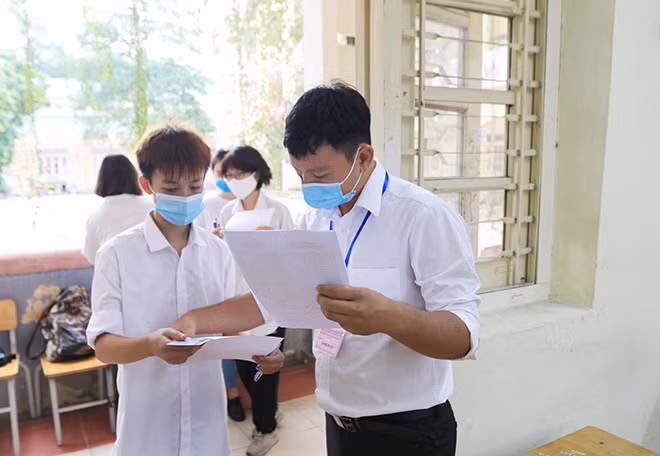 Đúng 7h, các thí sinh được gọi vào phòng thi. Các giám thị sẽ yêu cầu thí sinh bỏ khẩu trang để kiểm tra sau đó đeo trở lại và vào chỗ ngồi.