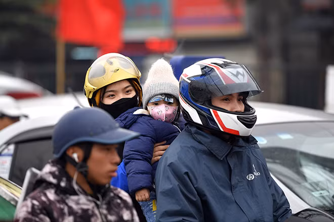 Em nhỏ với áo ấm, khăn trùm đầu theo bố mẹ về quê.