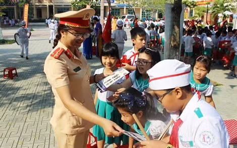 Thượng úy Phạm Thị Thu Thảo phát tờ rơi tuyên truyền về an toàn giao thông cho các em học sinh.