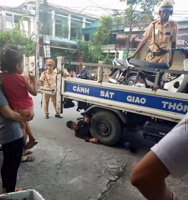 Chí phèo ôm bánh xe CSGT ăn vạ. Ảnh: Võ Chí Cường.