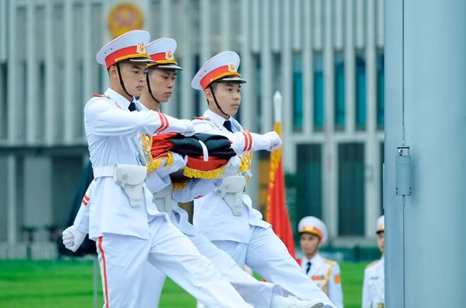 Ba chiến sĩ thực hiện nghi thức trang trọng tại chân cột cờ.