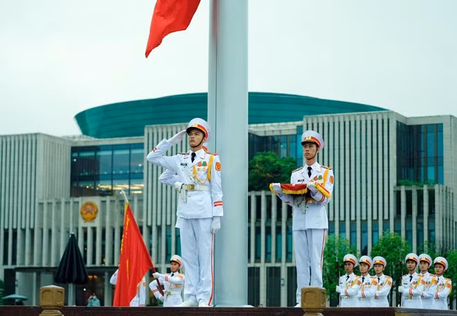 Quốc kỳ từ từ được kéo lên đến 2/3 cột cờ với băng vải đen buộc để cờ không bay.