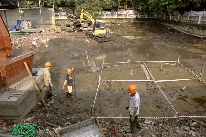 Công nhân thi công dự án cho biết, việc tu bổ, tôn tạo di tích được thực hiện từ 3 tuần trước. Trong những ngày gần đây do ảnh hưởng của mưa nên tiến độ đang chững lại. Ban ngày, lực lượng thi công hút hết nước trong hồ, ban đêm sẽ tiến hành nạo vét bùn.