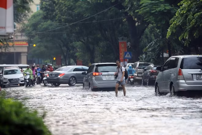 Phố Lý Thường Kiệt cũng là một trong nhiều điểm bị ngập sâu ở Hà Nội. Người đi bộ phải xắn quần lội qua dòng nước để di chuyển.