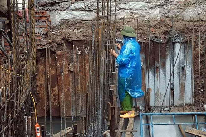 Một công nhân xây dựng mặc áo mưa để giữ ấm khi làm việc ngoài công trình.