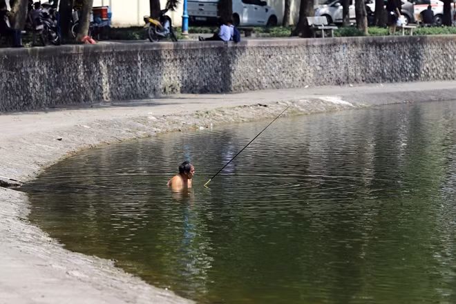 Một người đàn ông ngâm mình xuống dòng nước mát giữa trưa hè nắng gắt.