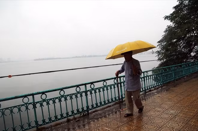 Cụ ông tản bộ sáng sớm bên bờ hồ Tây đã bị sương mù che phủ.