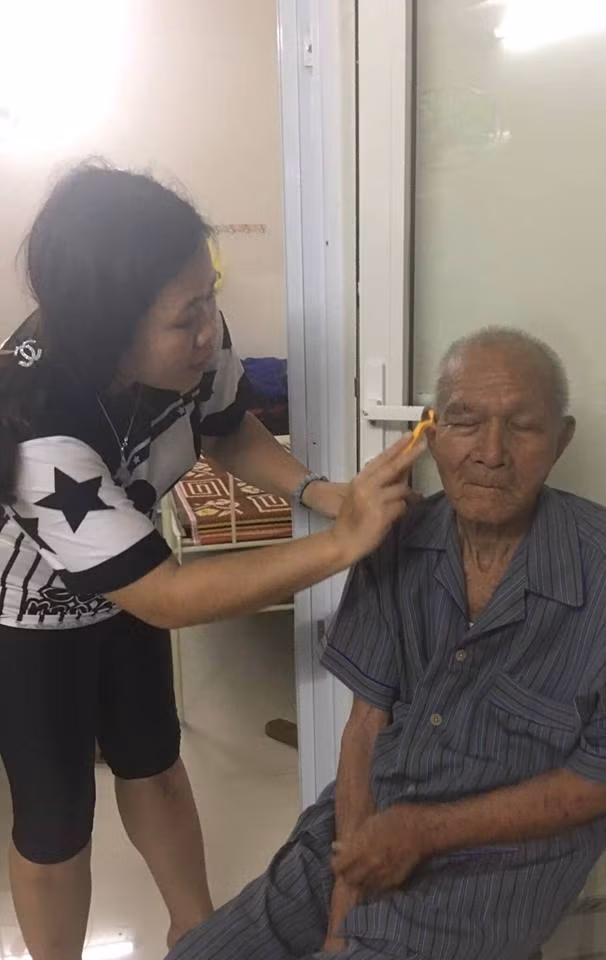 Cụ Quang đang được một tình nguyện viên chăm sóc.