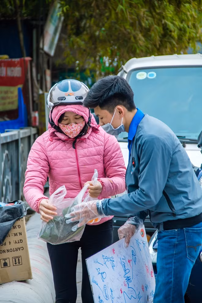 Các bạn trẻ đang giúp một người phụ nữ thả cá xuống sông Nhuệ.