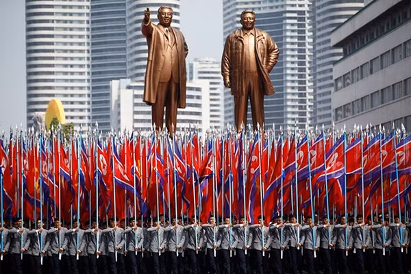 Người cầm cờ trước tượng Kim Nhật Thành và cố lãnh đạo Kim Jong-il. Ảnh: Reuters