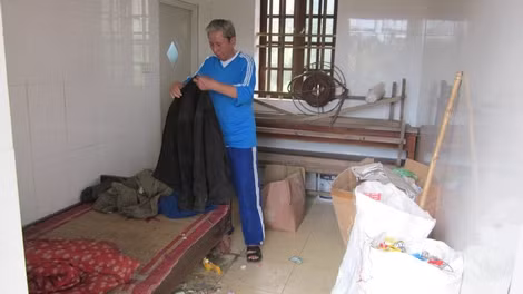 Người chú họ dọn dẹp lại chiếc giường ngủ cho ông Liêm.