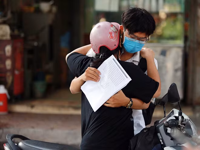 Một phụ huynh ôm động viên con làm bài tốt trước khi vào phòng thi