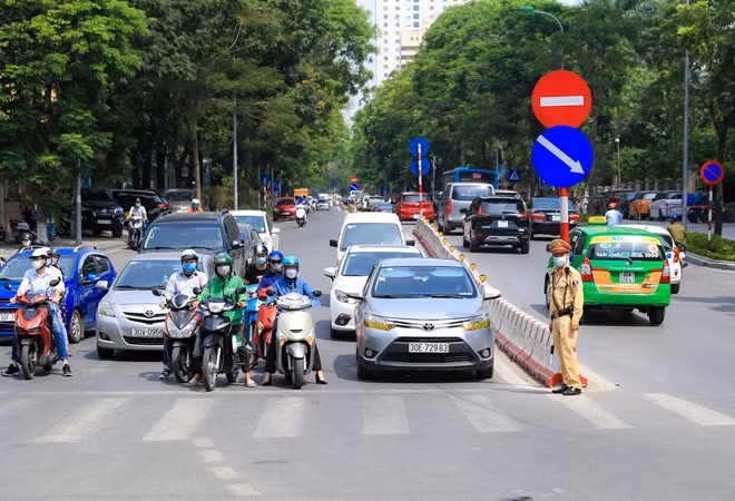 Khu vực nút giao thông Láng Hạ - Huỳnh Thúc Kháng, các chiến sĩ CSGT thuộc Đội CSGT số 3 vẫn túc trực điều tiết giao thông dưới thời tiết nắng nóng như thiêu đốt ở Hà Nội.