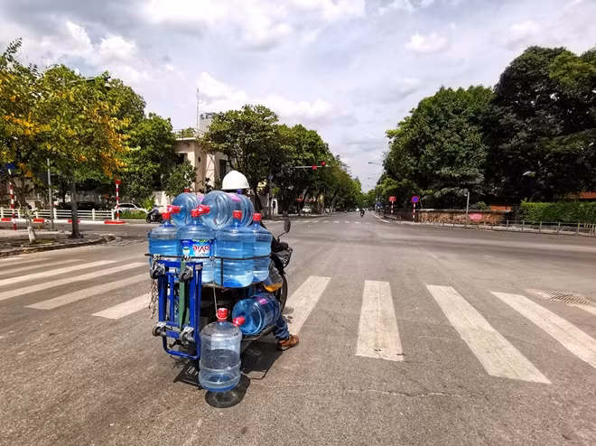 Dừng chờ đèn đỏ dưới cái nóng hầm hập phả lên từ mặt đường, Anh Toàn (Một người vận chuyển nước uống) chia sẻ, trời nắng nóng khiến lượng nước uống đóng chai to tiêu thụ rất nhanh, anh liên tục phải "ship" nước đến cho khách hàng từ sáng sớm đến cuối giờ chiều mới xong.