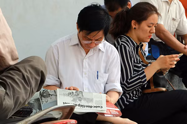 Một vài phụ huynh tranh thủ đọc báo trong lúc các thí sinh làm bài thi.