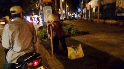 Bà cụ bán vé số vui mừng khi có người cho lộc.