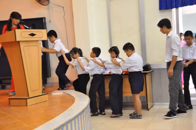 Nào! vịn vào vai nhau để cô dẫn lên sân khấu biểu diễn văn nghệ