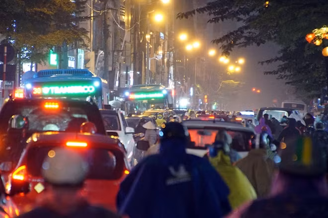 Người đi xe máy trùm kín áo mưa, run run chen chúc, chờ đợi di chuyển trong cơn mưa lạnh đến "thấu xương". Ô tô dàn hàng dài, lấn sang cả làn đường cho xe máy.