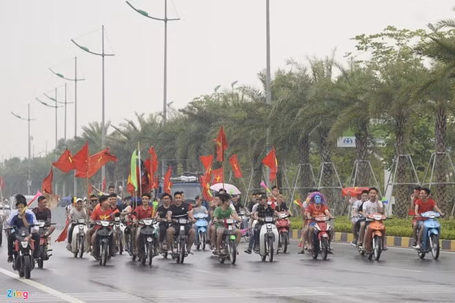 Nhiều đoàn cổ động viên phóng xe máy, vẫy cờ, hò hét dọc các tuyến đường nối với sân bay Nội Bài. Trước đó, Công an Hà Nội huy động hàng trăm cảnh sát thuộc nhiều lực lượng bảo vệ trật tự, phân làn giao thông. Ảnh: Zing.