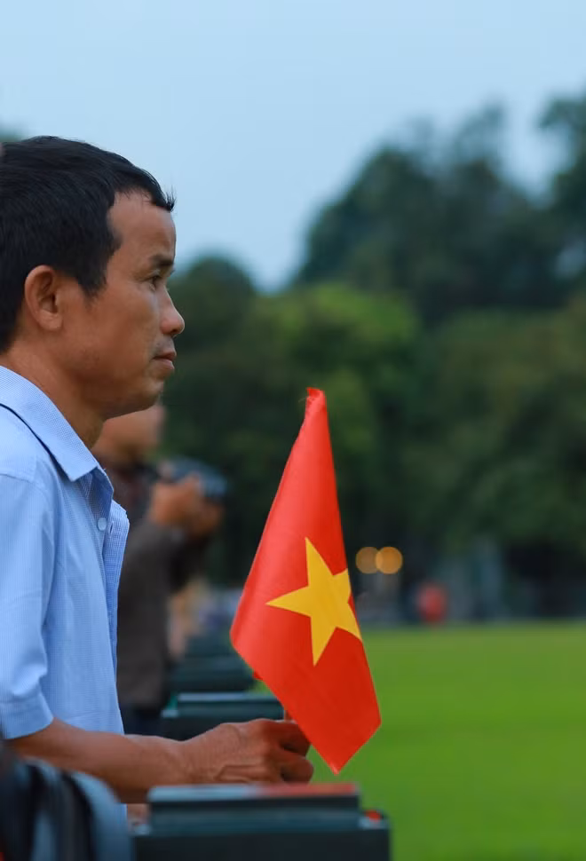 Mọi người dân từ già đến trẻ đều nghiêm trang hướng về cột cờ.