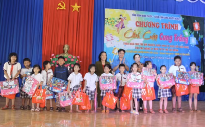 Bí thư Tỉnh Đoàn Bình Phước Trần Quốc Duy (hàng 2, đứng chính giữa) cùng hai nhà hảo tâm Nguyễn Thị Kim Mai (hàng 2, bên phải - phía ngoài cùng) và Huỳnh Nga (hàng 2, bên trái - phía ngoài cùng) trao quà Trung thu cho trẻ em xã Tân Hưng, huyện Hớn Quản tại chương trình “Chú Cuội Cung Trăng”