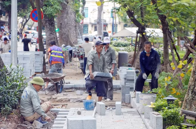 Tại một điểm thi công vỉa hè trên phố Hàng Khay, công nhân làm việc hoàn toàn không đeo khẩu trang.