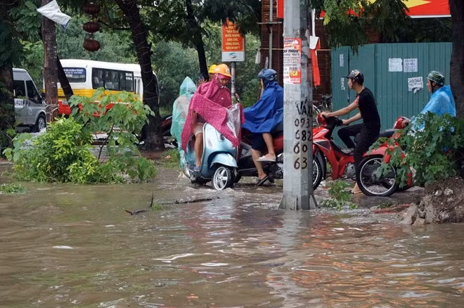 Nhiều người dân đi xe máy cố len lỏi trên vỉa hè để qua điểm ngập.