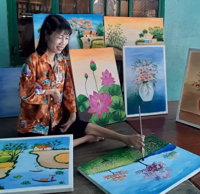 Họa sĩ khuyết tật Huỳnh Thị Xậm bên những bức tranh của mình.