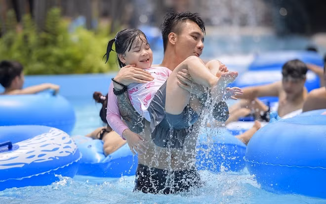 Các bạn nhỏ được phụ huynh cho tha hồ nghịch trong hồ tạo sóng.