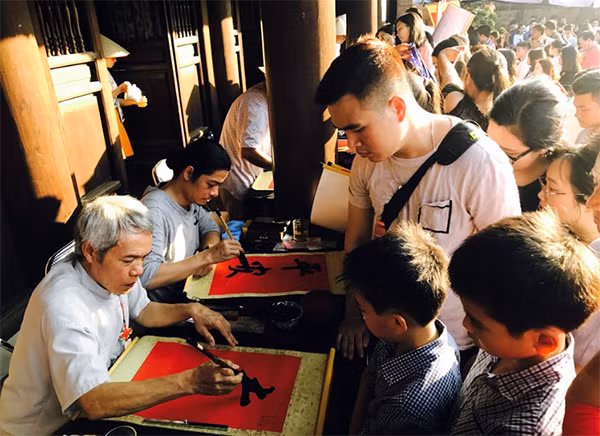 Gia đình anh Quang (Nam Định) chăm chú theo dõi từng nét chữ của ông đồ.