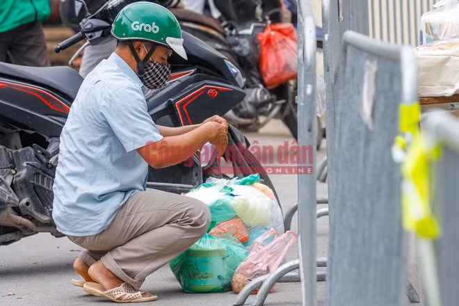 Do bị phong tỏa trong đêm nên nhiều bệnh nhân bên trong bệnh viện đã phải nhờ người thân tiếp tế đồ dùng, nhu yếu phẩm. Hình ảnh người đàn ông kiểm tra lại đồ tại chốt kiểm soát bên ngoài bệnh viện E vào sáng nay (20/8)