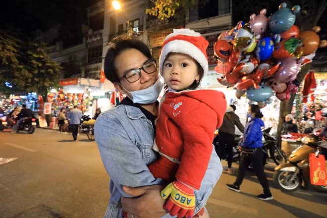 Em nhỏ bên bố ra phố đón không khí Giáng sinh trong tiết trời lạnh giá của mùa Đông.