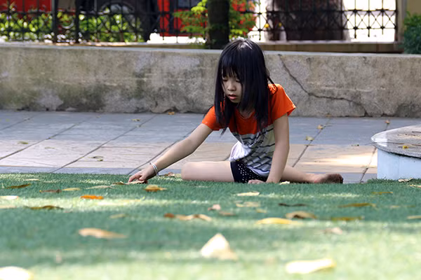 Một bé gái mải miết nhặt những chiếc lá rụng để đan thành vòng tay cho mình. Một bé gái mải miết nhặt những chiếc lá rụng để đan thành vòng tay cho mình.